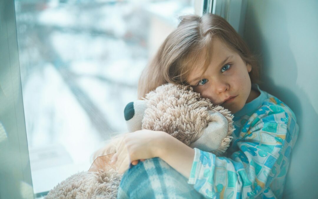 girl in blue white and red plaid shirt hugging brown teddy bear