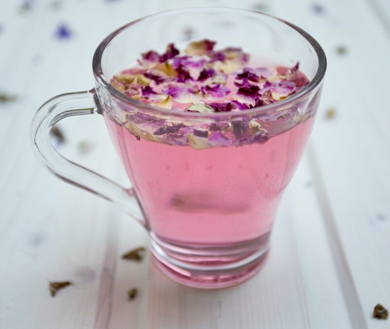 clear glass cup surrounded by petals