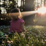 girl sitting on daisy flowerbed in forest