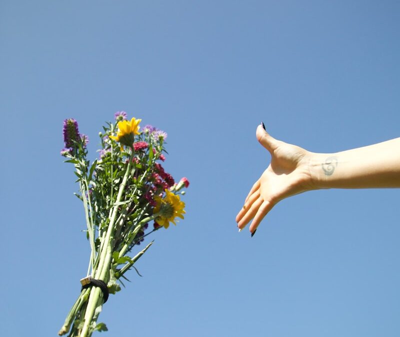 a hand reaching for a bouquet of flowers