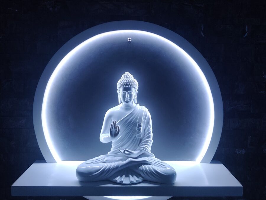 a buddha statue sitting in front of a blue light